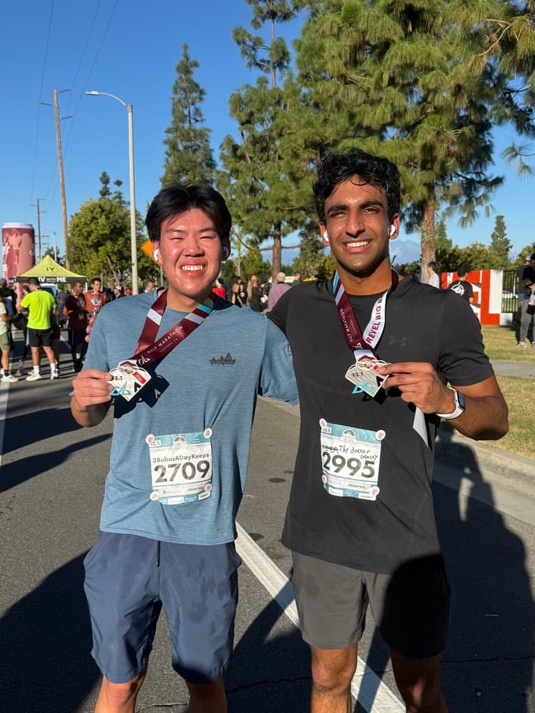 Jethro Chu and a fellow runner holding their finisher medals after a race.